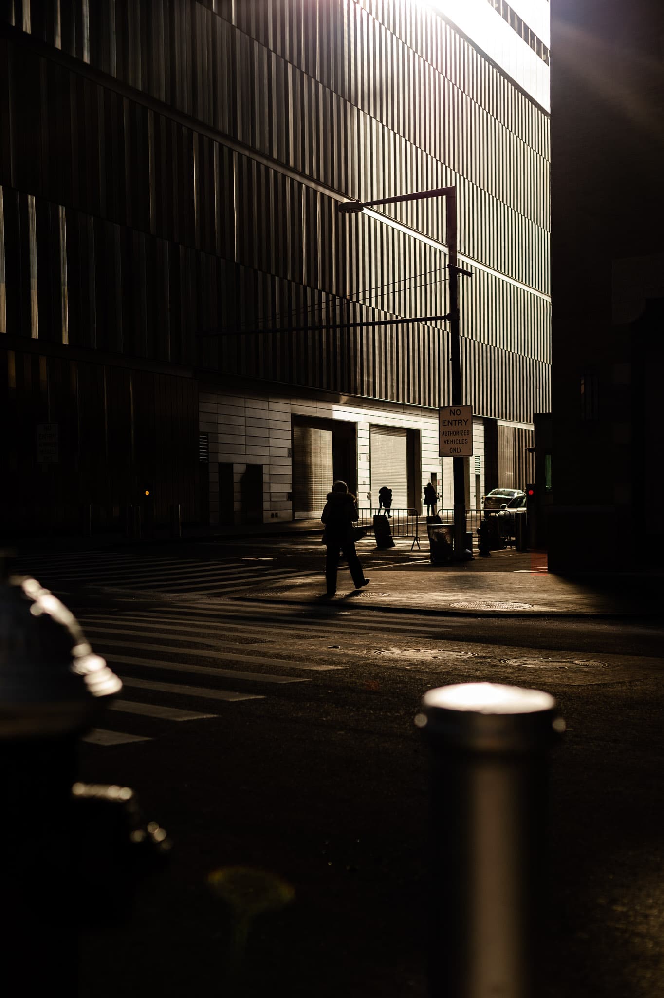 A pedestrian crossing the street with a beam of light reflecting off the Freedom Tower located in New York, NY.